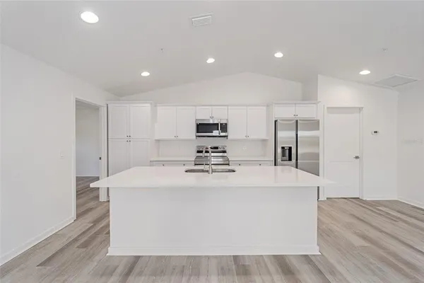 a large white kitchen with wooden floor and a sink