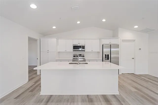 a large white kitchen with wooden floor and a sink