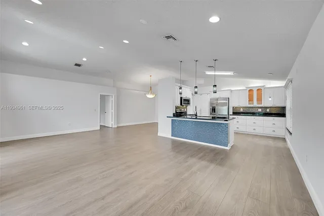 a large kitchen with stainless steel appliances kitchen island a large counter top and a stove top oven