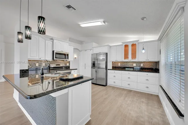 a kitchen with stainless steel appliances kitchen island granite countertop a stove a sink and a refrigerator