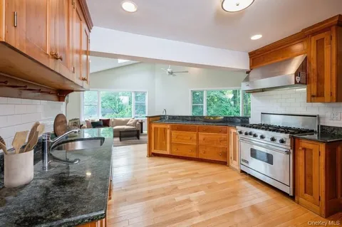 a kitchen with stainless steel appliances granite countertop a sink a stove and a wooden floors