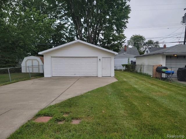 21828 Rausch Avenue Eastpointe, MI 48021 - Photo 3 of 15 Detached garage with a paneled door and a side entry door, concrete driveway, and a chain-link fence