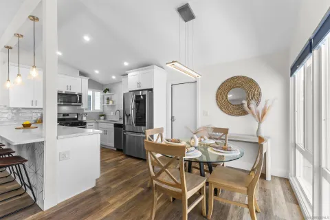 a kitchen with stainless steel appliances kitchen island granite countertop a refrigerator a stove top oven a sink dishwasher and white cabinets with wooden floor