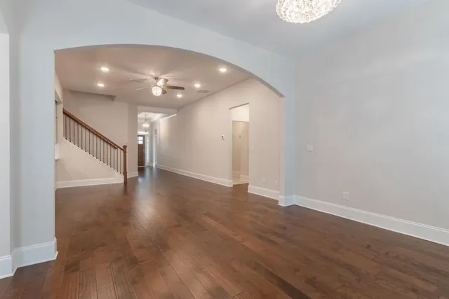an empty room with wooden floor chandelier and windows