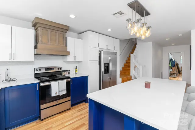 a kitchen with stainless steel appliances a table chairs in it and wooden floors