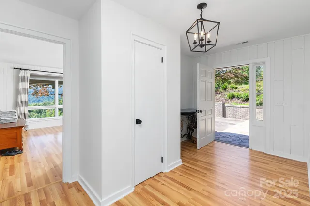 a view of a hallway with wooden floor and a chandelier