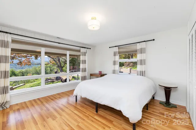 a bedroom with a bed and a large window with outer view