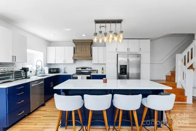 a kitchen with stainless steel appliances granite countertop a dining table and chairs