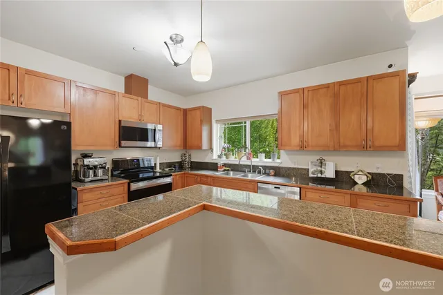 a kitchen with stainless steel appliances granite countertop a sink a stove top oven a granite counter space and cabinets