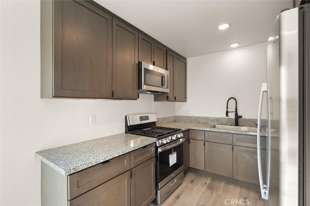 19237 Bryant Street, Unit 16 Northridge, CA 91324 - Photo 4 of 15 a kitchen with stainless steel appliances granite countertop a sink stove and cabinets