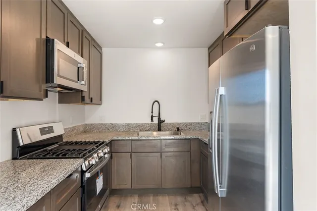 a kitchen with stainless steel appliances granite countertop a sink stove and refrigerator