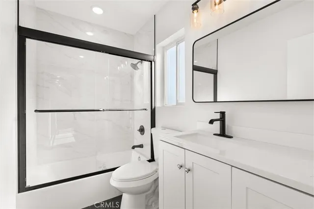 a bathroom with a granite countertop sink mirror vanity and toilet