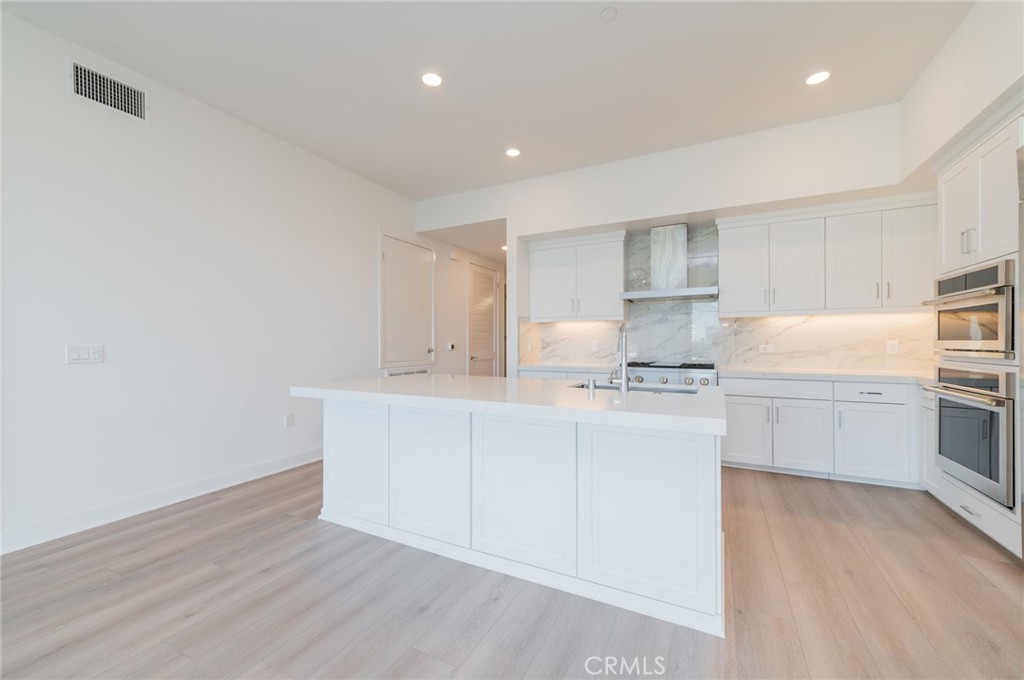 1703 Rivington Irvine, CA 92612 - Photo 8 of 42 a kitchen with cabinets wooden floor and stainless steel appliances