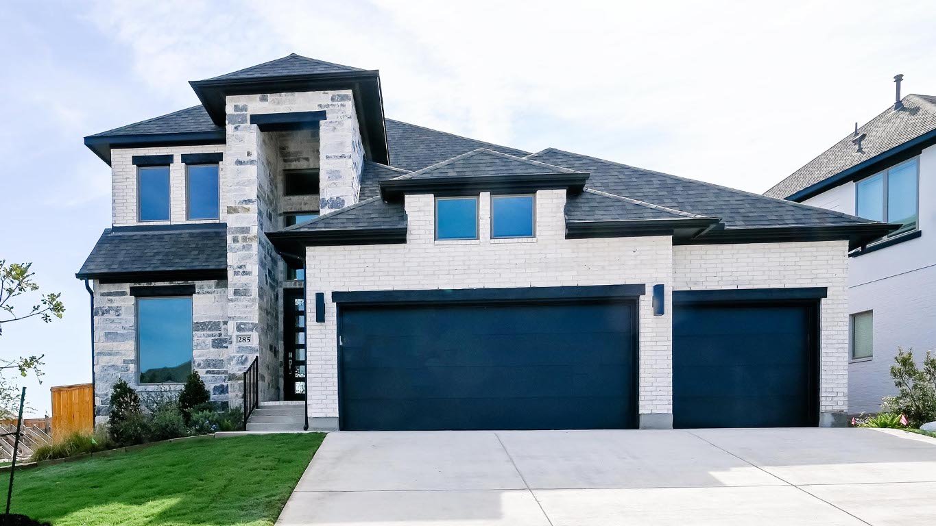View of front of house with an attached garage, driveway, a front lawn, and a shingled roof