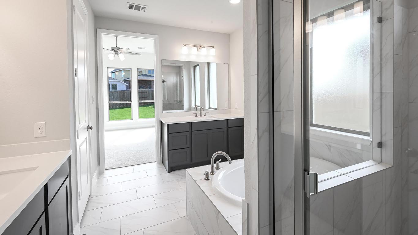285 Prickly Poppy Loop Kyle, TX 78640 - Photo 20 of 40 Full bath with two vanities, a garden tub, a marble finish shower, and ceiling fan