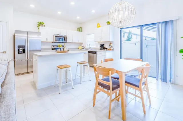 a kitchen with stainless steel appliances a refrigerator a stove a dining table and chairs with wooden floor