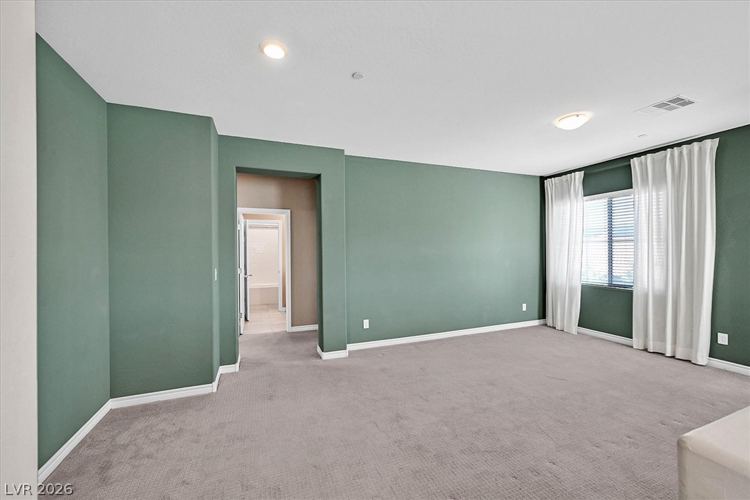 1106 Langston Ranch Avenue Henderson, NV 89002 - Photo 14 of 36 A spacious primary bedroom with plush carpet flooring and ample natural light through well-appointed windows.