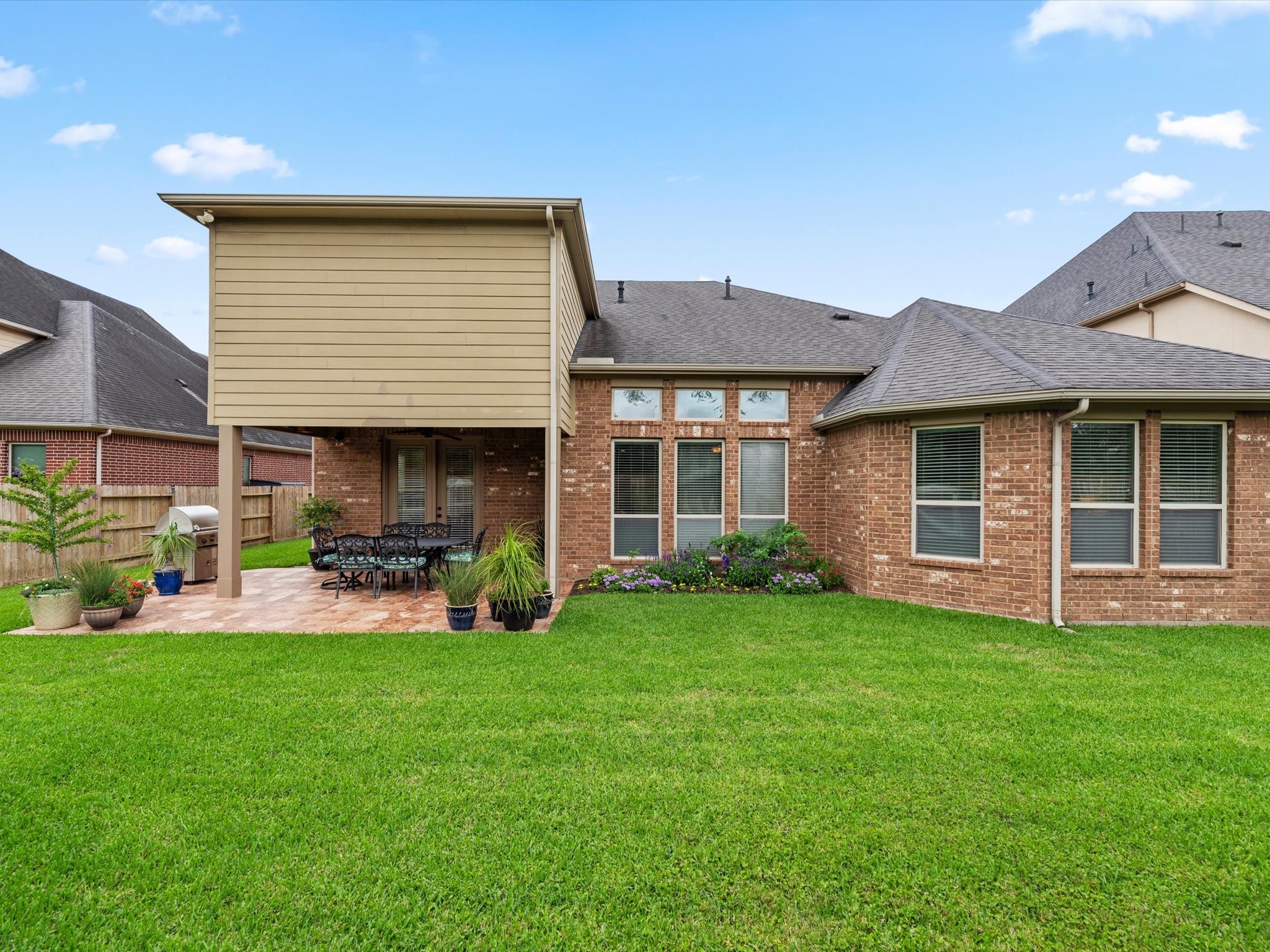 3907 Randle Ridge Court Fulshear, TX 77441 - Photo 37 of 46 This photo shows the backyard of a brick home with a covered patio area featuring room for outdoor furniture. The yard has a well-maintained lawn, including yard lights, offering a great space for outdoor gatherings.
