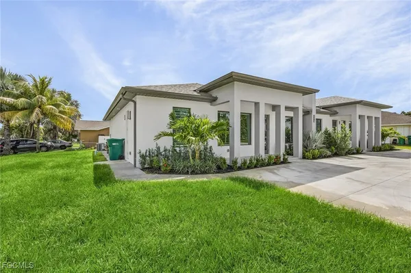 a front view of a house with a yard and potted plants