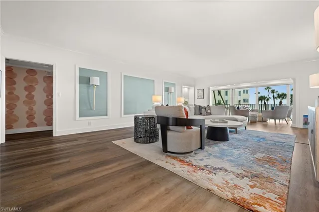 a living room with couches a coffee table and kitchen view with wooden floor