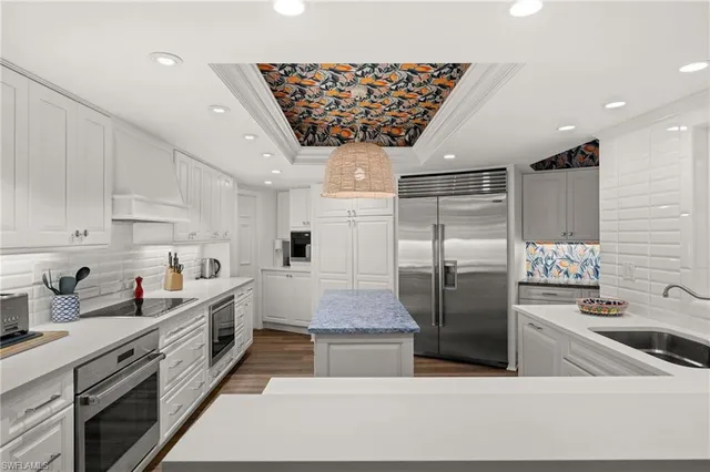 a kitchen with stainless steel appliances granite countertop a refrigerator a sink dishwasher a stove and white cabinets