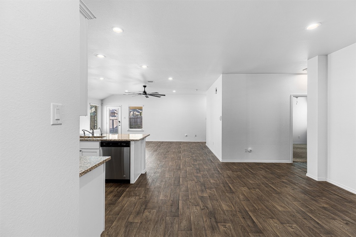 16016 Birch Bay Lane Conroe, TX 77384 - Photo 15 of 37 an empty room with wooden floor and kitchen view