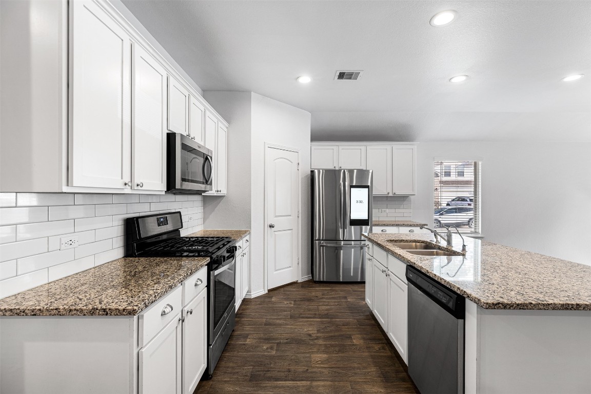 16016 Birch Bay Lane Conroe, TX 77384 - Photo 21 of 37 a kitchen with stainless steel appliances granite countertop a stove top oven a refrigerator a sink and dishwasher with wooden floor