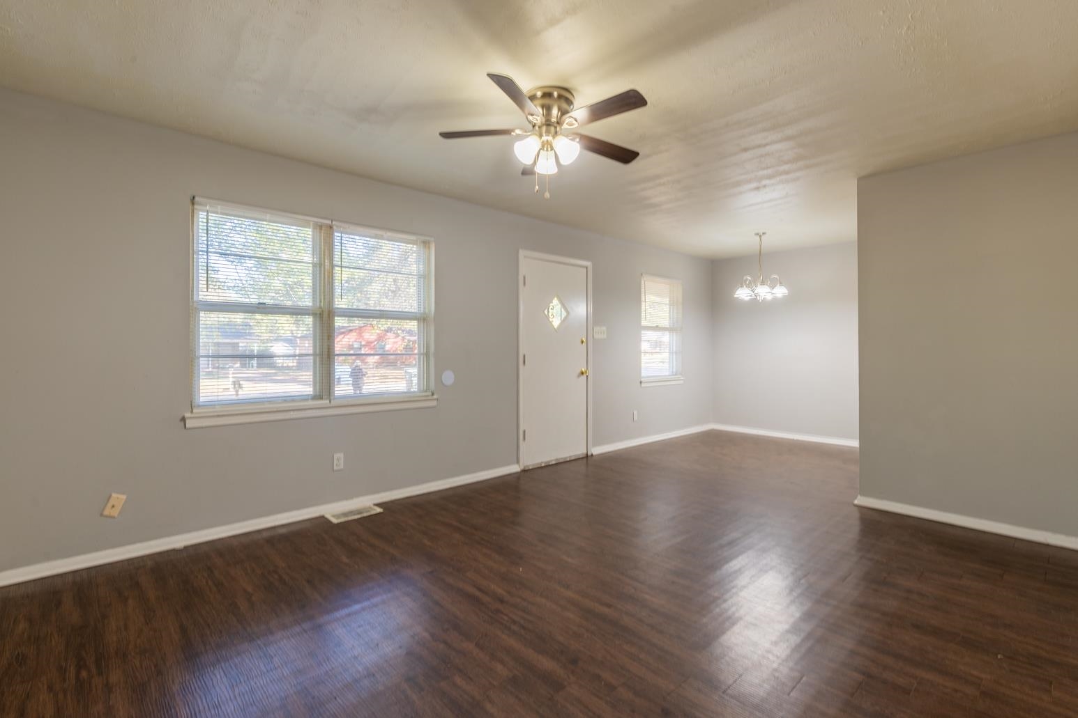 5581 Lochinvar Road Memphis, TN 38116 - Photo 5 of 19 a view of an empty room with wooden floor and a window