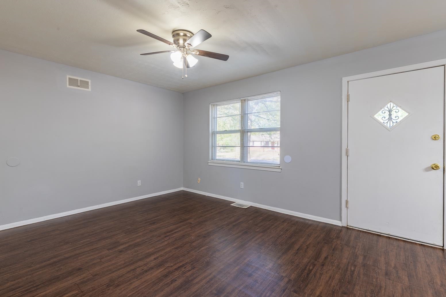 5581 Lochinvar Road Memphis, TN 38116 - Photo 6 of 19 a view of an empty room with a window and wooden floor