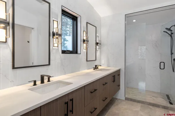 a bathroom with a double vanity sink a mirror and a shower