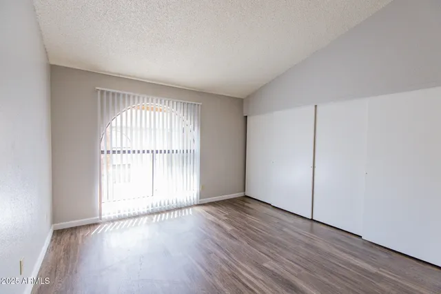 an empty room with wooden floor and windows with curtains