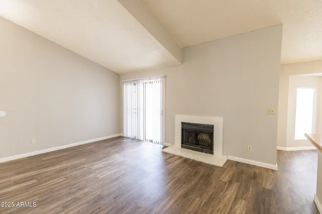 an empty room with wooden floor fireplace and windows