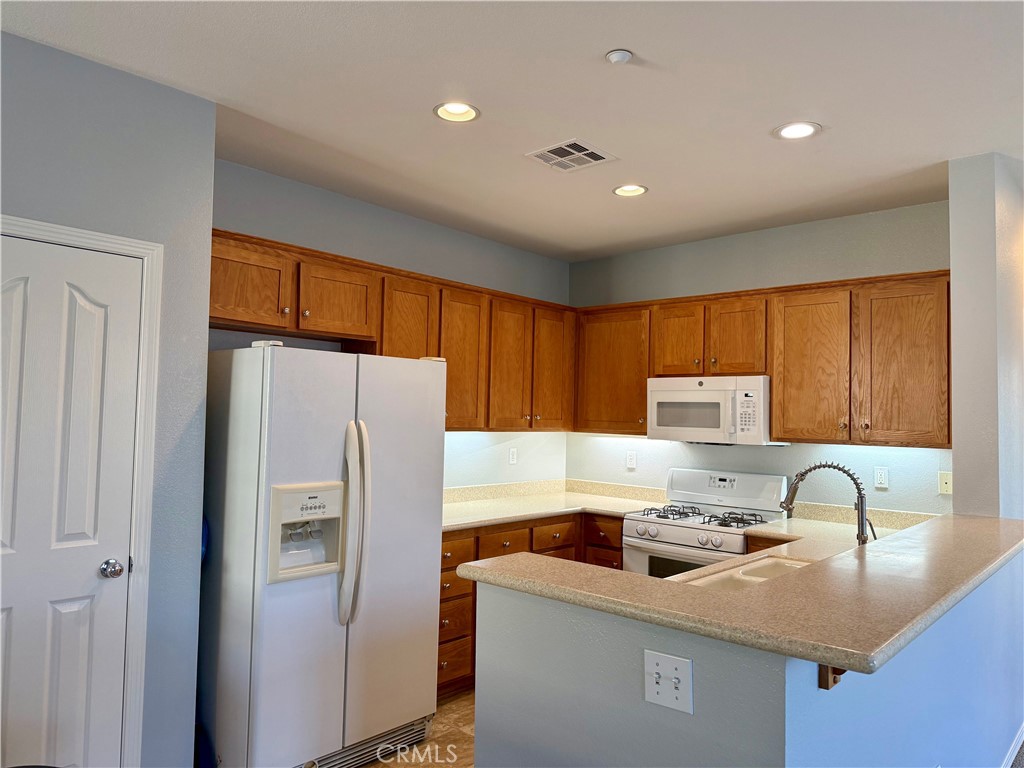 36368 Grazia Way Winchester, CA 92596 - Photo 15 of 27 a kitchen with stainless steel appliances granite countertop a refrigerator a sink a stove and a refrigerator with wooden cabinets