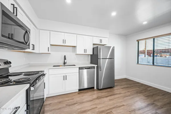 a kitchen with stainless steel appliances granite countertop a stove a sink dishwasher a refrigerator and a microwave oven with wooden floor