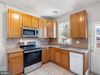 a kitchen with stainless steel appliances granite countertop white cabinets granite counter tops and a window