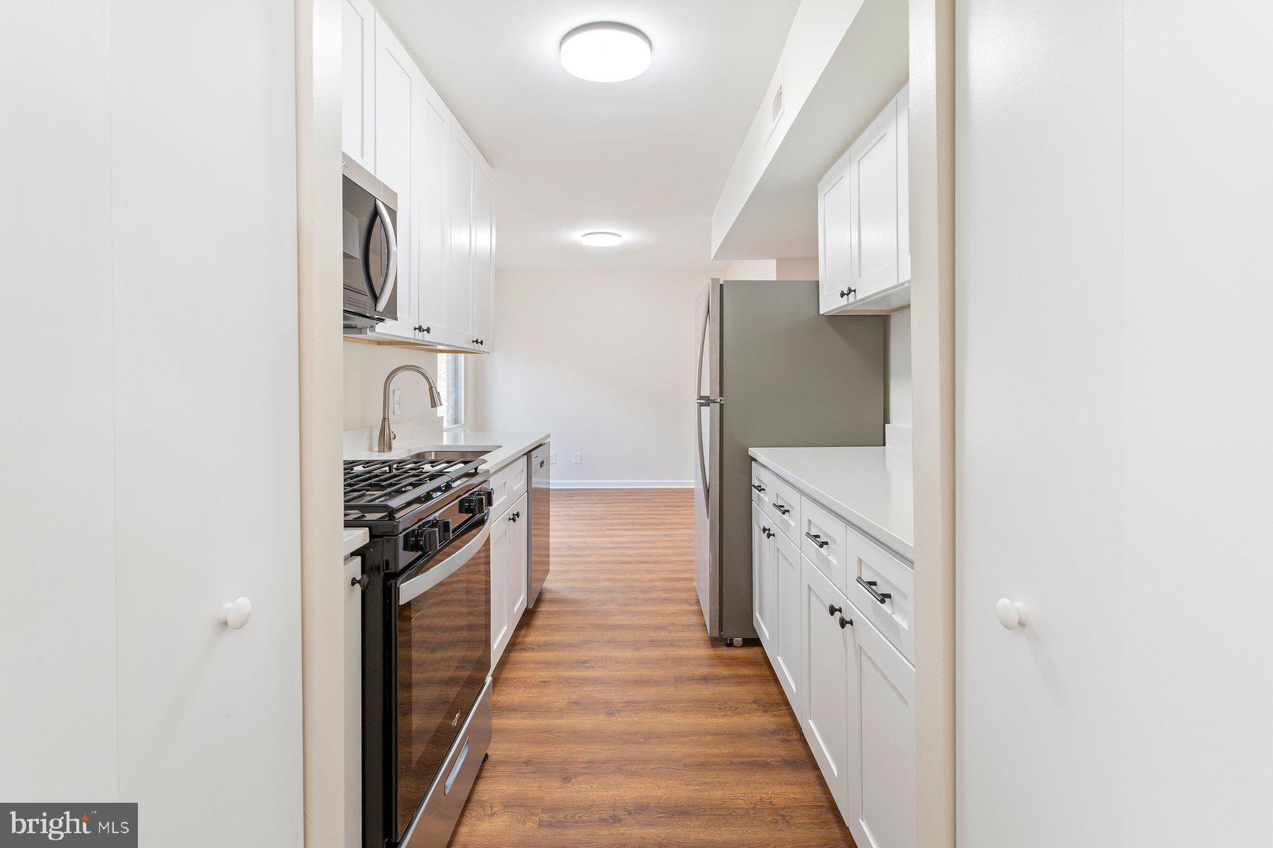11234 Cherry Hill Road, Unit 304 Beltsville, MD 20705 - Photo 14 of 28 a large white kitchen with granite countertop a sink and stainless steel appliances