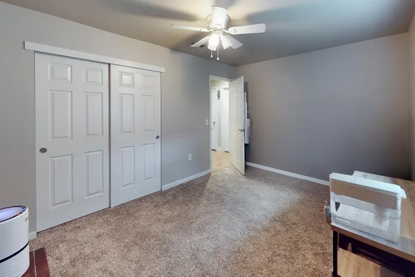 a view of an empty room and chandelier fan