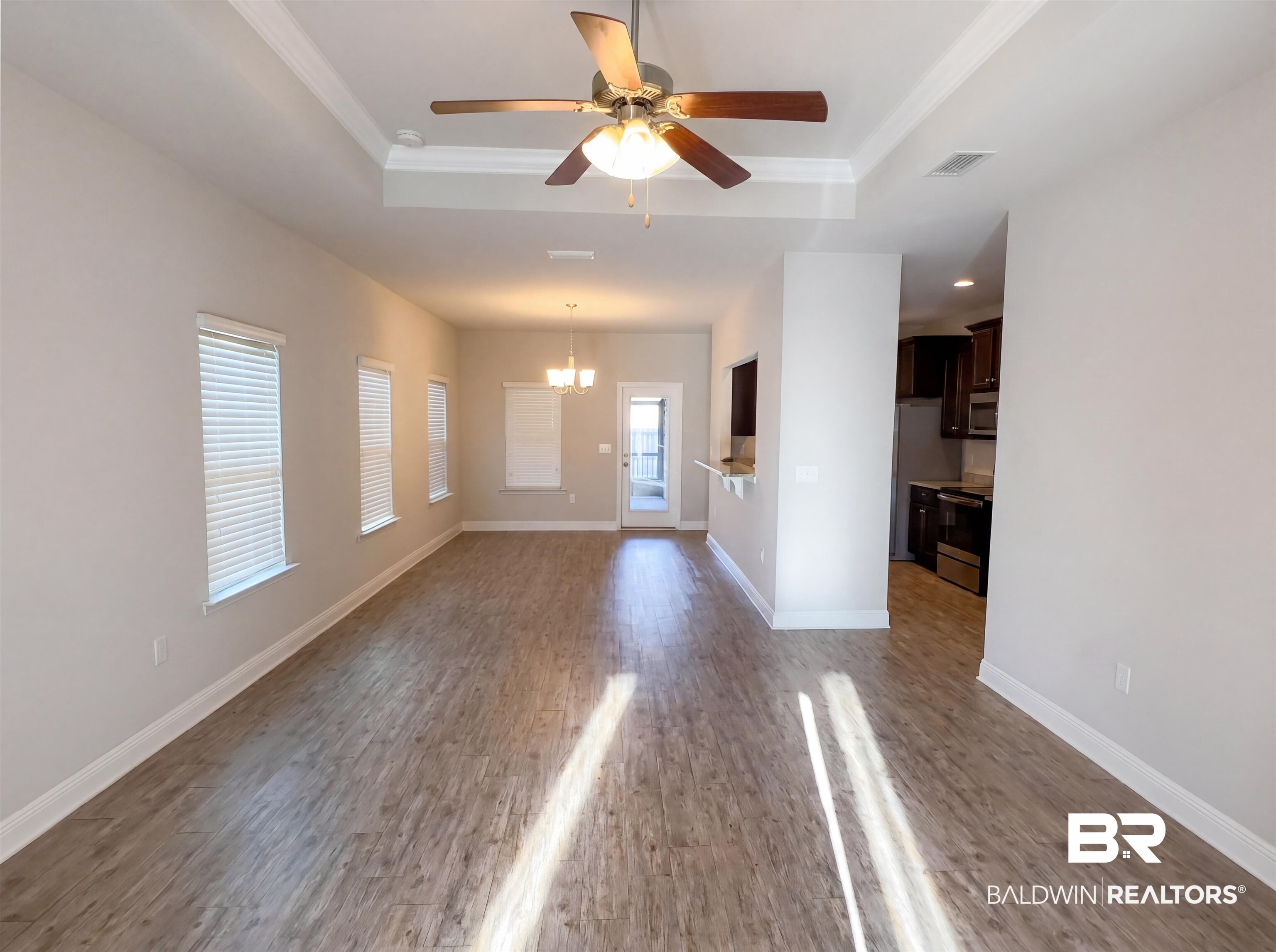 1740 Covington Lane Foley, AL 36535 - Photo 3 of 18 Spacious living area featuring wood-finish flooring, a tray ceiling with a ceiling fan, and multiple windows with blinds