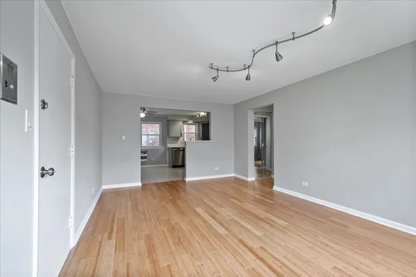 a view of a big room with wooden floor and windows