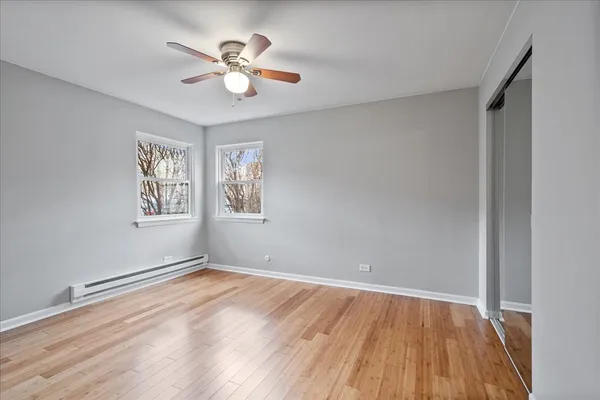 a view of empty room with wooden floor and fan