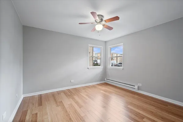 a view of empty room with wooden floor and fan