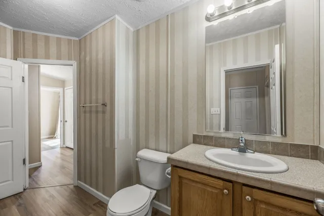 a bathroom with a granite countertop sink toilet and mirror