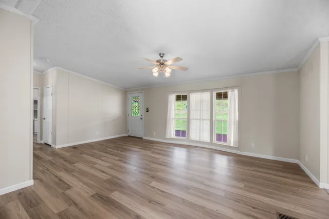 a view of an empty room with a window and wooden floor