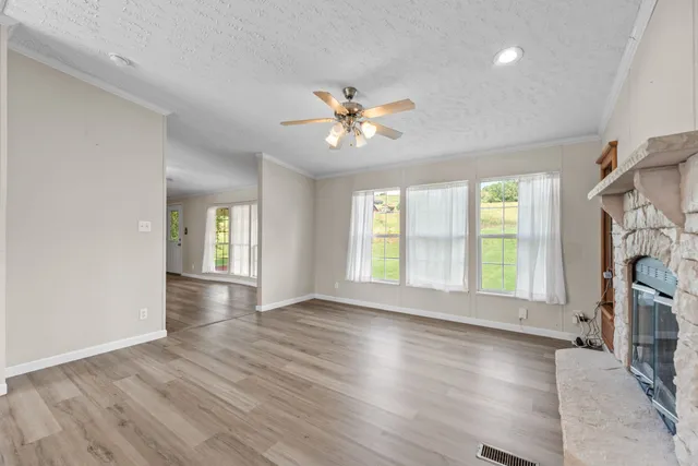 a view of an empty room with a window and wooden floor
