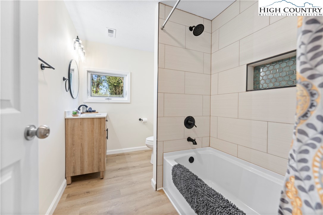 90 Camp Branch Road Waynesville, NC 28786 - Photo 4 of 34 a bathroom with a tub a sink and wooden floor