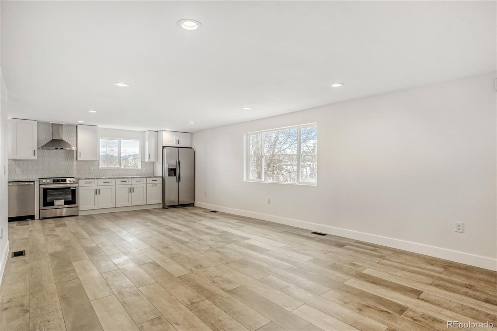 1057 Meade Street Denver, CO 80204 - Photo 4 of 38 an empty room with kitchen and windows