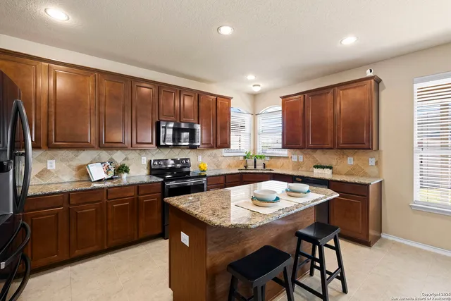 a kitchen with a sink a stove a refrigerator cabinets and dining table