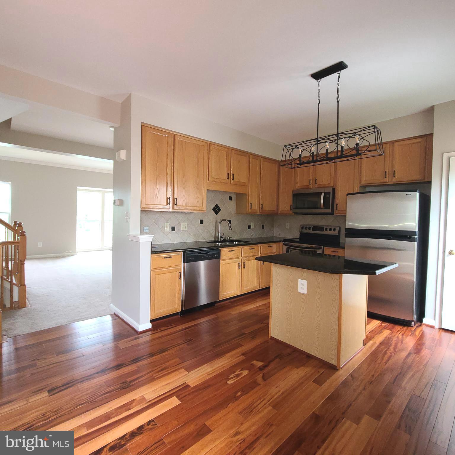 43393 Chokeberry Square Ashburn, VA 20147 - Photo 21 of 31 a kitchen with kitchen island granite countertop a stove a sink and a refrigerator
