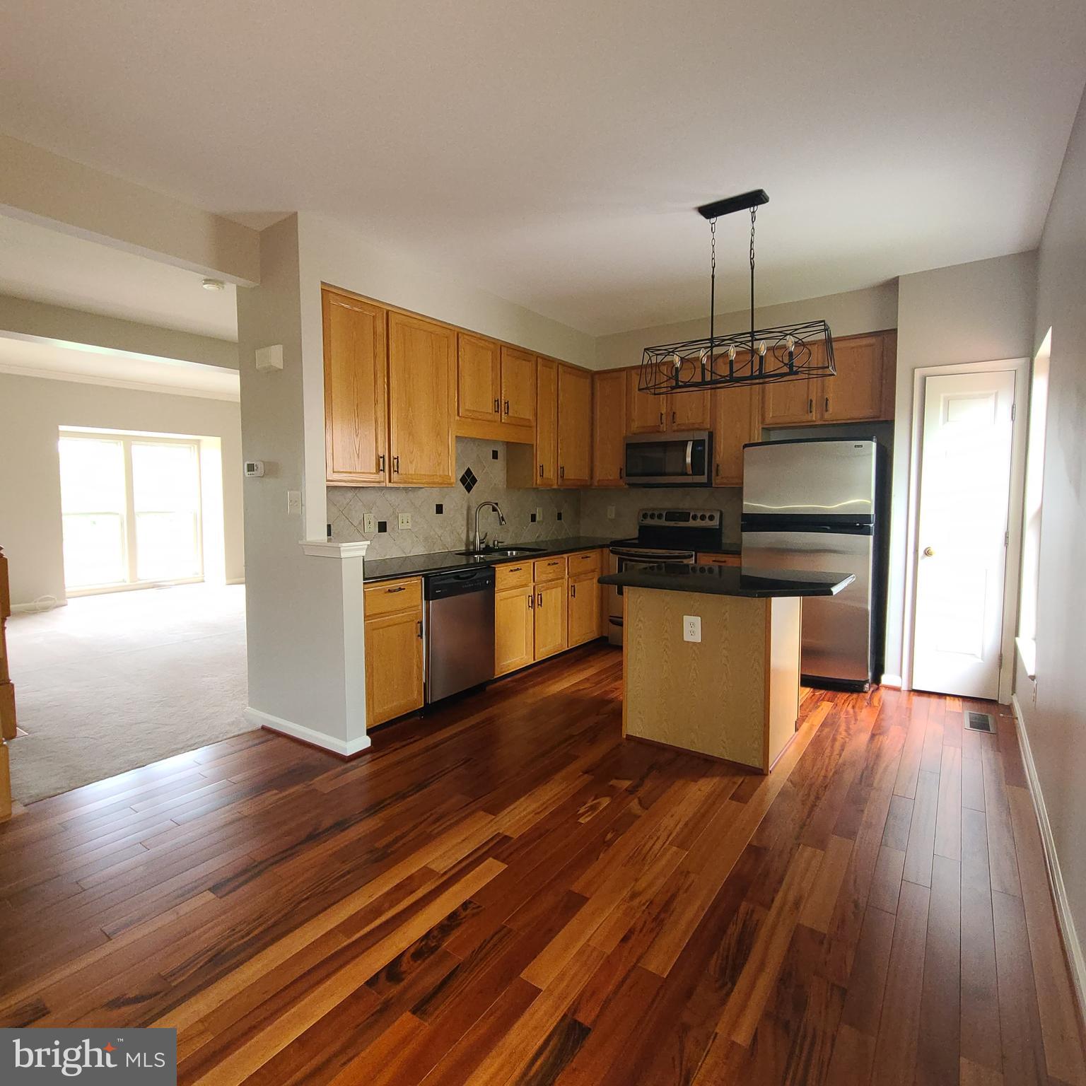 43393 Chokeberry Square Ashburn, VA 20147 - Photo 7 of 31 a kitchen with stainless steel appliances granite countertop a stove a refrigerator and a wooden floors