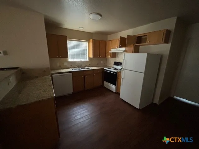 a kitchen with stainless steel appliances granite countertop a refrigerator a stove a sink and a microwave oven with wooden floor